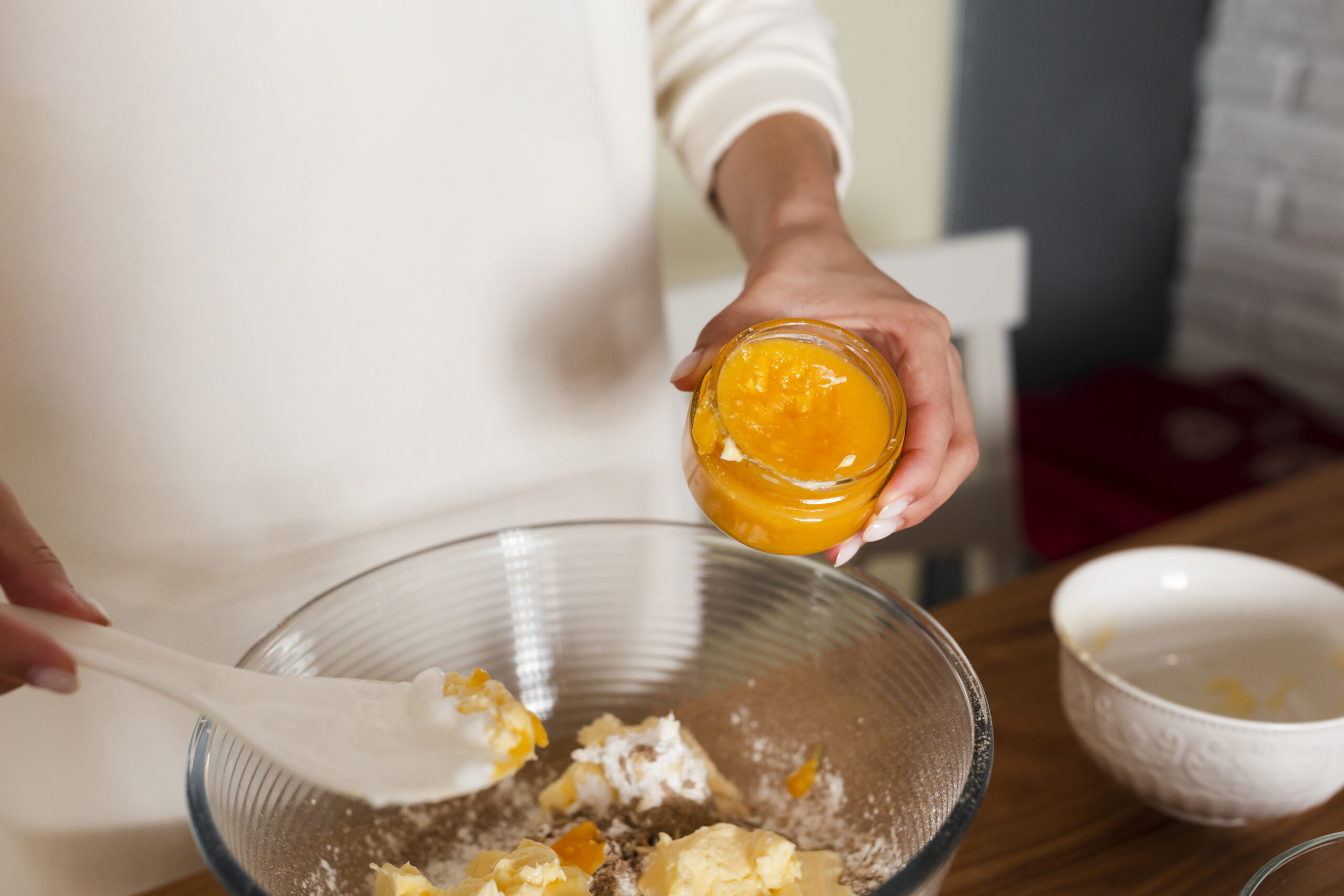 Baking process for carrot cake, showing a baker creaming butter and another mixing oil into batter.